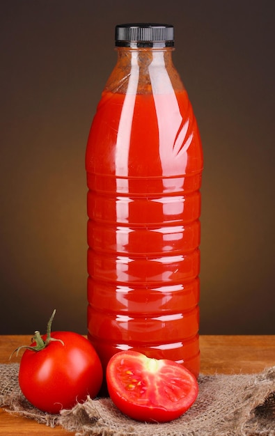 Succo di pomodoro in bottiglia sulla tavola di legno su sfondo marrone