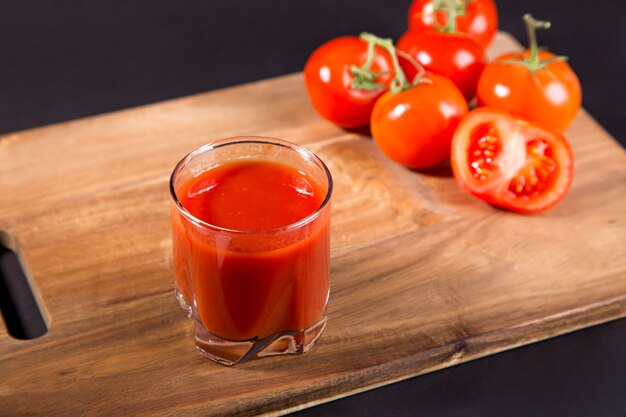 Succo di pomodoro in un bicchiere e pomodori freschi in tavola