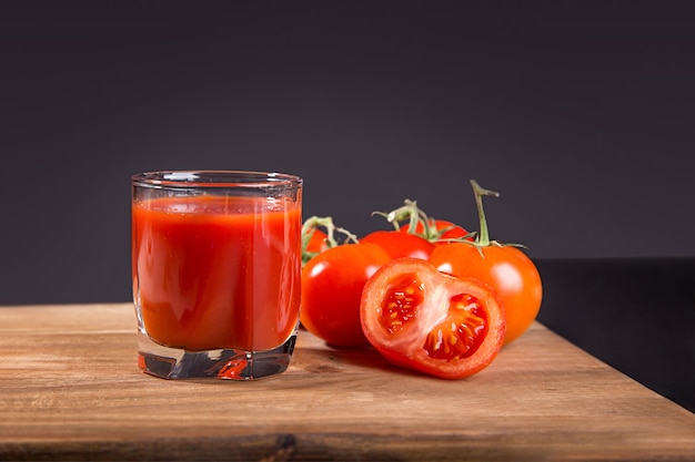 Succo di pomodoro in un bicchiere e pomodori freschi in tavola