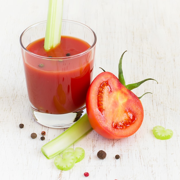 Succo di pomodoro in vetro con sedano su uno sfondo bianco