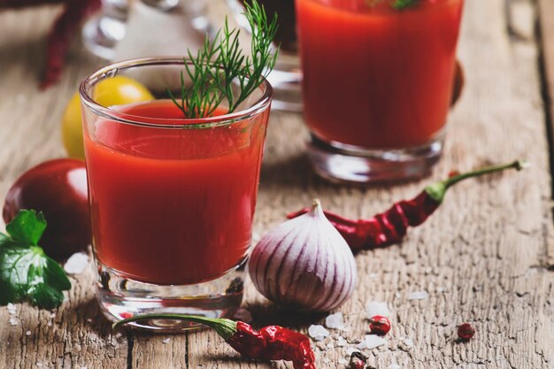 Succo di pomodoro piccante con sale e spezie sfondo in legno vintage fuoco selettivo in stile rustico