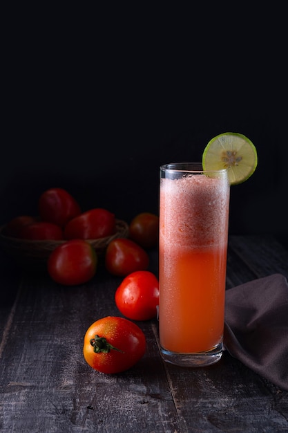 Succo di pomodoro servito su un tavolo con pomodori sparsi sul lato