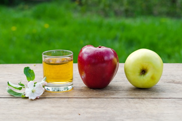 Succo e mele di mele su una tavola di legno con una tovaglia grigia di erba verde