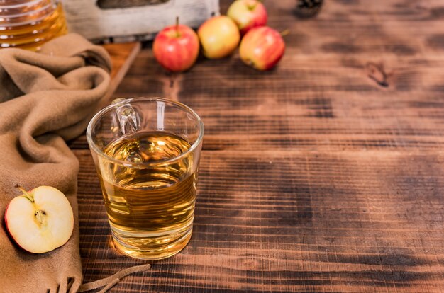 Succo fresco con mele rosse mature biologiche in scatola di legno. Cornucopia del raccolto autunnale nella stagione autunnale. Bevande e frutta con sfondo tavolo in legno.