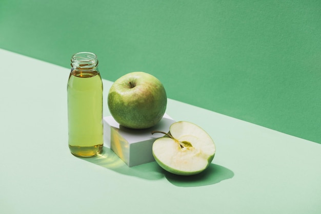 Succo fresco vicino a mele e cubo bianco su sfondo verde e turchese