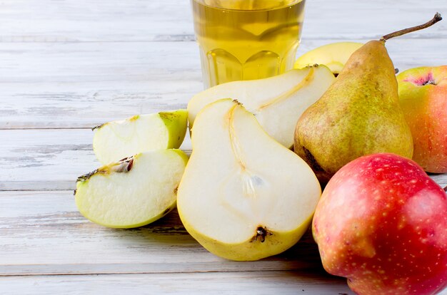 succo in un bicchiere e mele mature e pere su un tavolo di legno