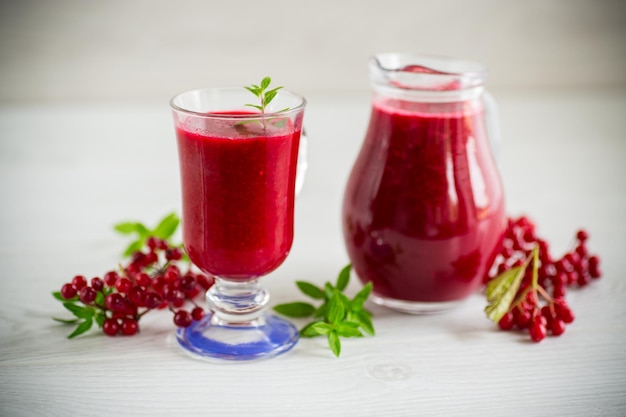 succo naturale denso appena spremuto con polpa di viburno rosso maturo in un decanter su un tavolo di legno