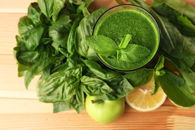 Succo verde sano con frutta ed erbe sulla tavola di legno da vicino