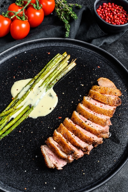 Succose bistecche di petto d'anatra con asparagi caramellati. Sfondo nero. Vista dall'alto