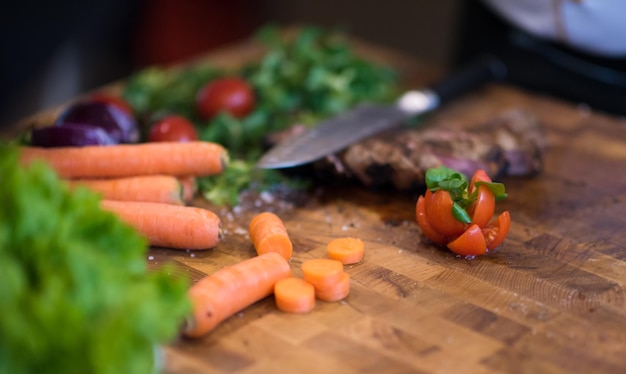 Succose fette di bistecca alla griglia con verdure su una tavola di legno