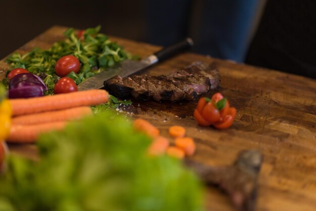 Succose fette di bistecca alla griglia con verdure su una tavola di legno