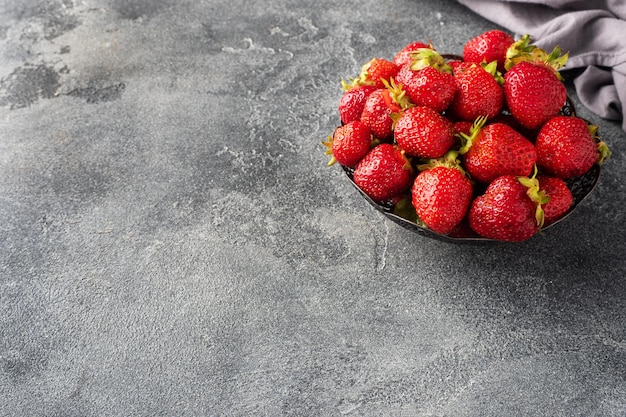 Succose fragole mature in un piatto su uno sfondo di cemento Dolce sano dessert vitamina raccolto spazio copia