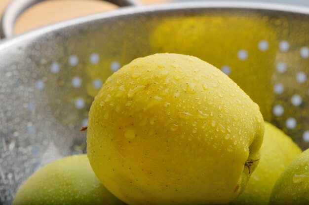 Succose mele gialle fresche con gocce d'acqua in un coltello da cucina per tagliare le mele