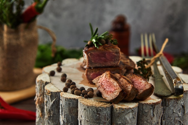 Succosi pezzi medi di costata di manzo bistecca con gli occhi in una padella su una tavola di legno con una forchetta e un coltello