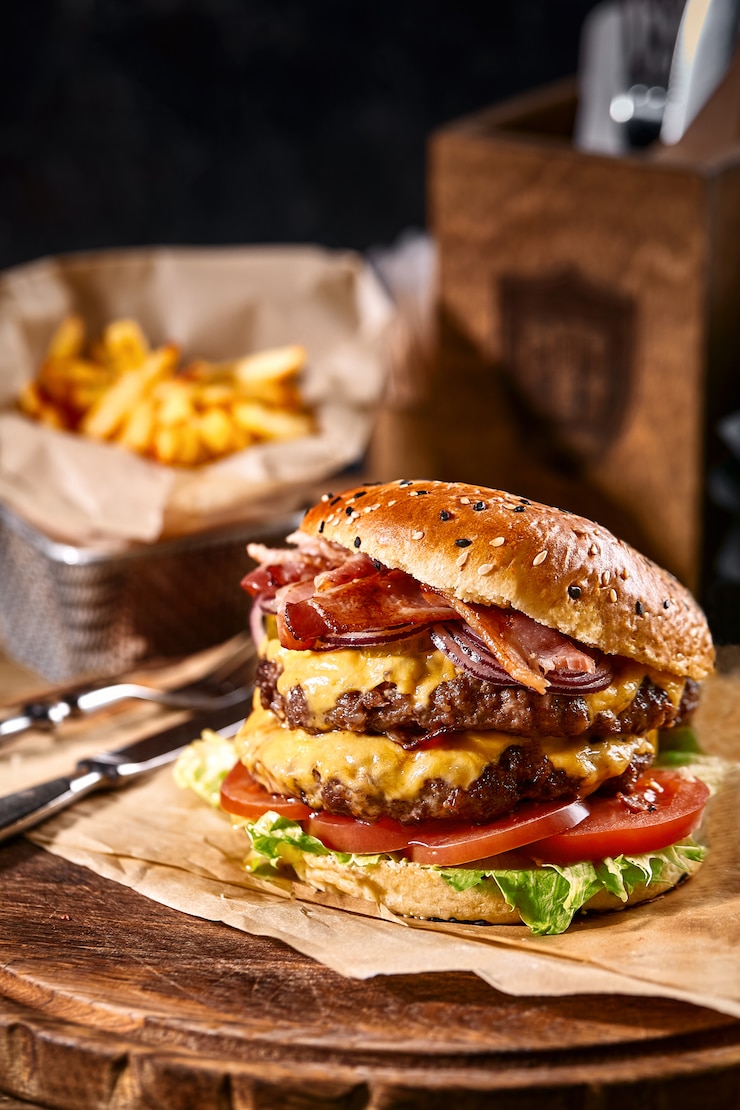Foto succoso hamburger americano, hamburger o cheeseburger con due polpette di manzo, con salsa e crogiolarsi su uno spazio nero