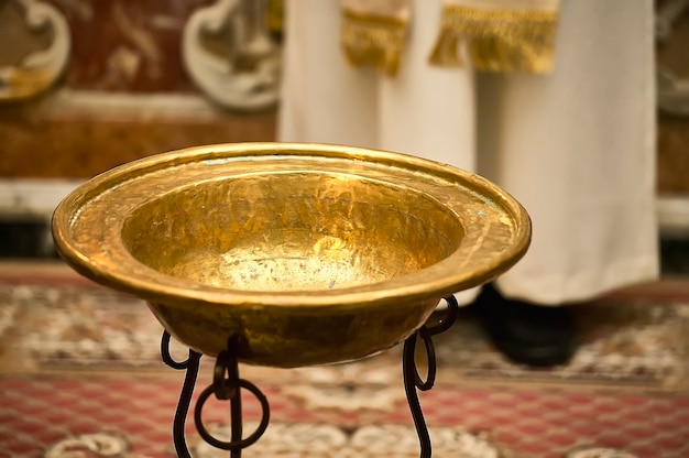 Suggestiva immagine del battesimo cattolico con la coppa d'oro per mettere l'acqua santa