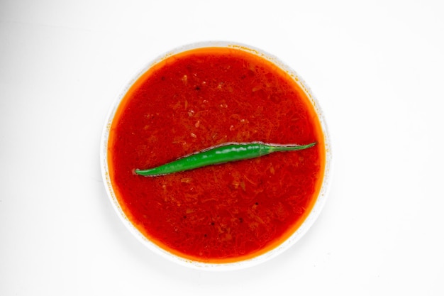 Sugo al curry di pesce rosso disposto in una ciotola bianca e guarnito con peperoncino verde su sfondo bianco