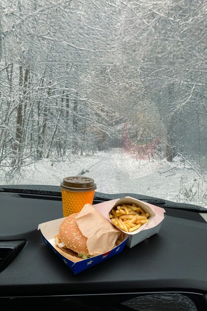 Sul cruscotto dell'auto ci sono hamburger, patatine fritte e caffè