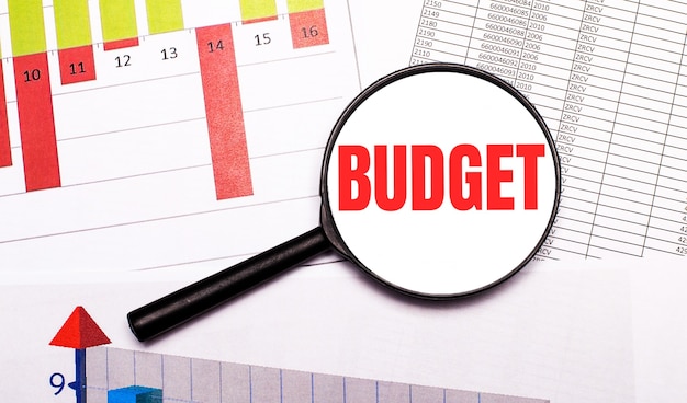 Sul desktop, grafici, report, una lente d'ingrandimento con la scritta BUDGET. Concetto di affari