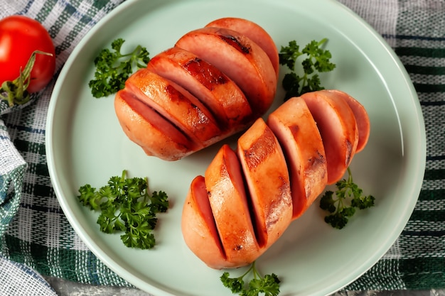 Sul piatto ci sono salsicce alla griglia con verdure fresche