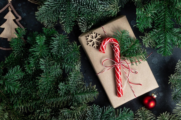 Sul tavolo c'è un regalo circondato da rami di alberi di Natale, giocattoli di legno e spezie