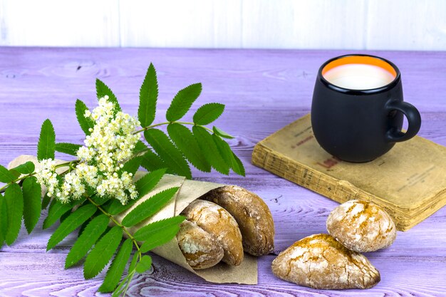 Sul tavolo, fiori primaverili, una tazza di latte e biscotti fatti in casa.