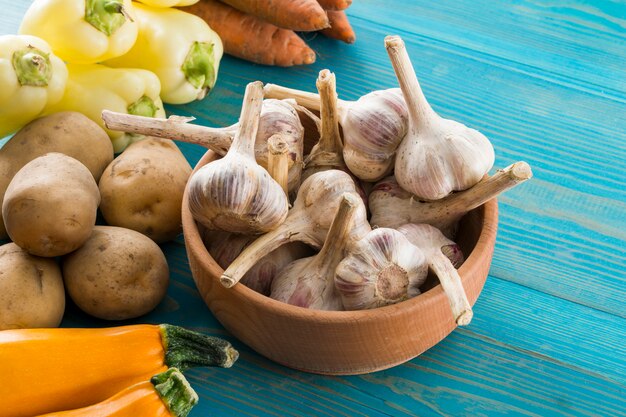 Sul tavolo l'aglio in una ciotola e accanto alle verdure