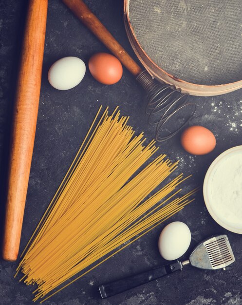 Sul tavolo uova, farina, pasta e utensili da cucina