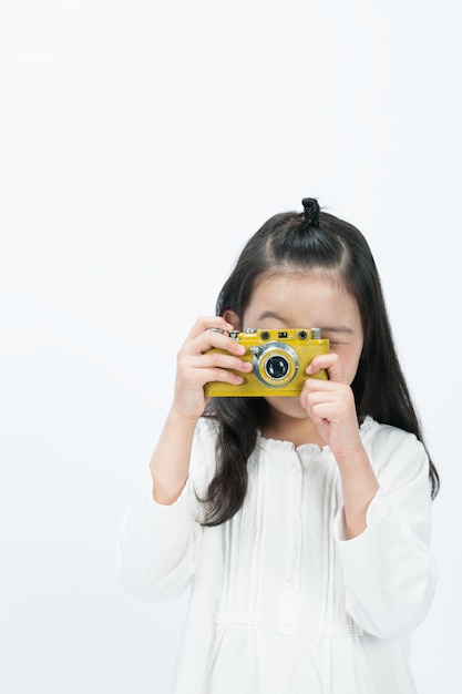 Sullo sfondo bianco, un bambino sta filmando la parte anteriore con una macchina fotografica.