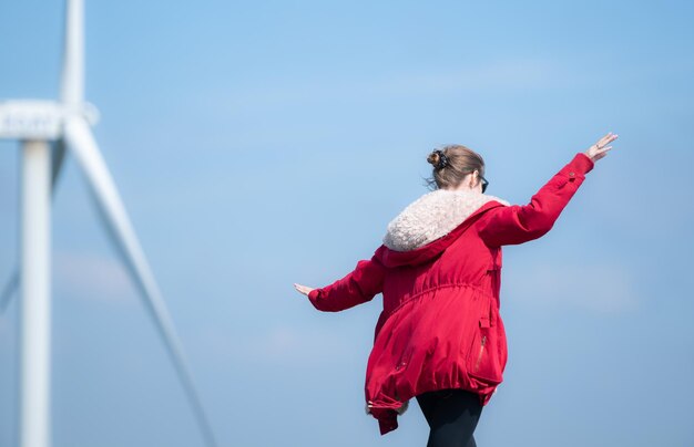 Sullo sfondo dei mulini a vento una giovane donna con una giacca rossa si sta godendo le sue vacanze invernali