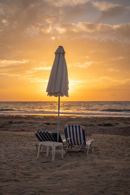 Sunset con due lettini e un ombrello da spiaggia verticale