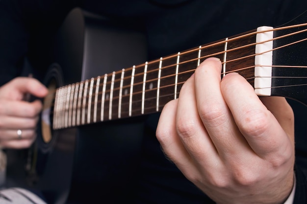 Suonare la chitarra nera con le mani della chitarra si chiuda