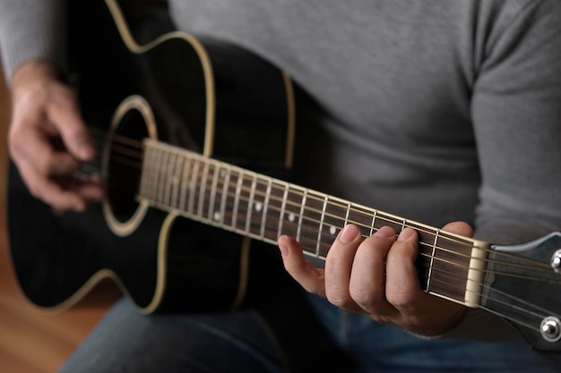 Suonare la chitarra Strimpellare la chitarra acustica nera Il musicista suona la musica Uomo dita che tiene il mediatore Mano maschile che suona il collo della chitarra nella stanza buia Persona irriconoscibile che prova il primo piano della tastiera