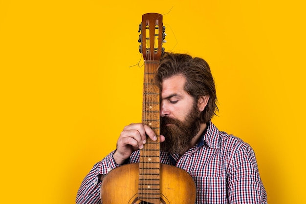 Suonare la melodia musicista maturo e cantante chitarrista in stile casual moderno hipster barbuto con chitarra acustica concetto musicale brutale bell'uomo con baffi suonare la chitarra