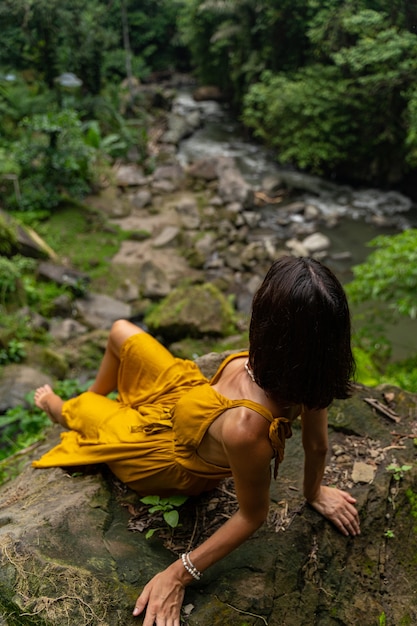 Suoni di fiume. Attraente persona di sesso femminile appoggiata alla pietra, in attesa di correre il fiume di montagna