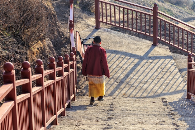 Suora buddista che cammina giù per le scale a Larung gar in una calda e nebbiosa mattina, nel Sichuan