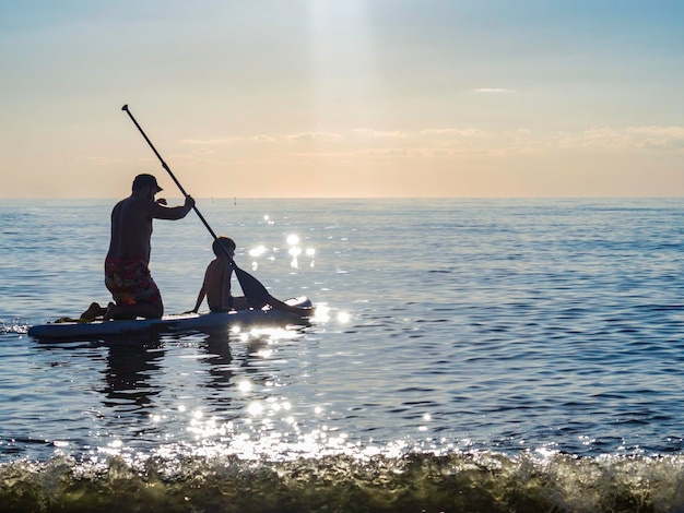 Sup surf training padre e sole nuotano in mare aperto su SAP surfing