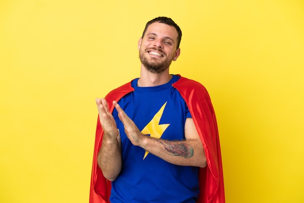 Super eroe brasiliano uomo isolato su sfondo giallo che applaude dopo la presentazione in una conferenza