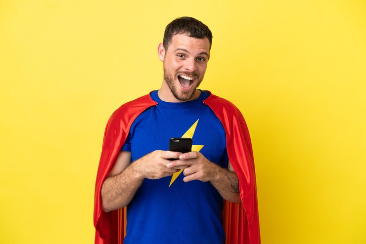 Foto super eroe brasiliano uomo isolato su sfondo giallo sorpreso e inviando un messaggio