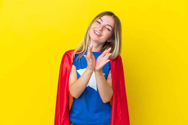 Super eroe donna rumena isolata su sfondo giallo che applaude dopo la presentazione in una conferenza