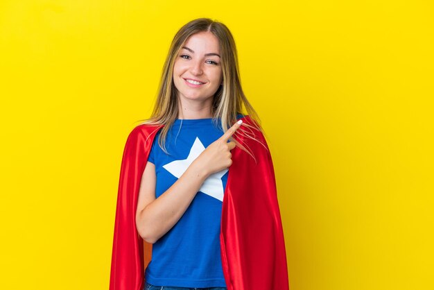 Super eroe donna rumena isolata su sfondo giallo che punta al lato per presentare un prodotto