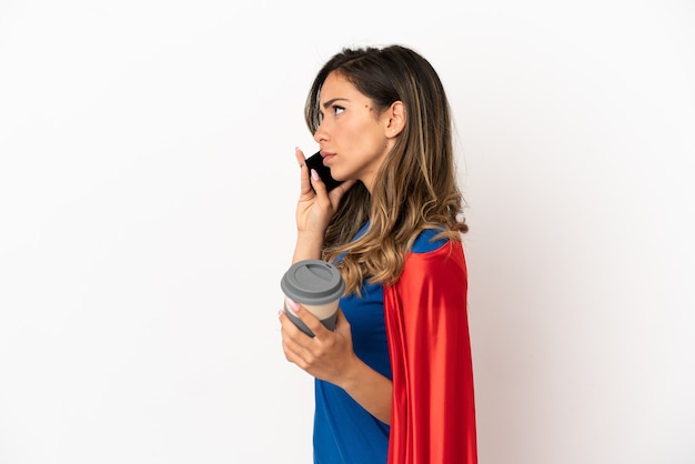 Super eroe donna su sfondo bianco isolato tenendo il caffè da portare via e un cellulare