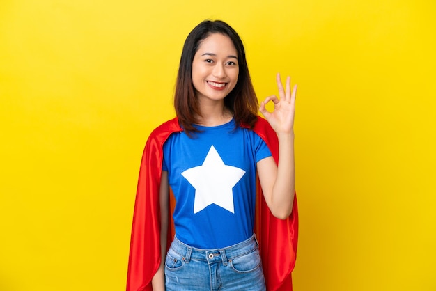 Super eroe donna vietnamita isolata su sfondo giallo che mostra il segno giusto con le dita