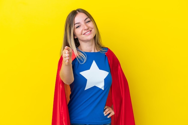 Super Hero Donna rumena isolata su sfondo giallo che stringe la mano per chiudere un buon affare