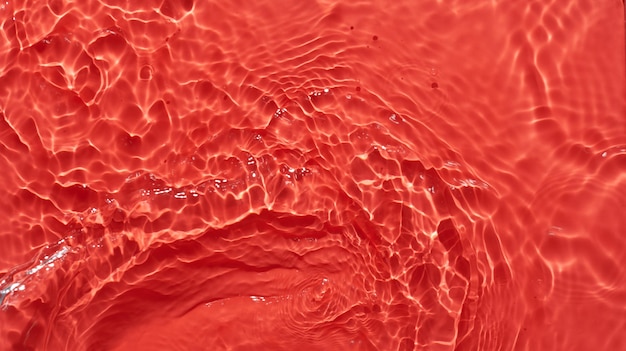 Superficie d'acqua rossa sfondo astratto onde e onde consistenza di idratante aqua cosmetico con bolle