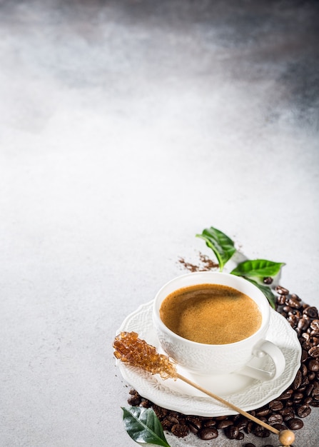 Superficie del caffè con appena preparato in una tazza bianca con fagioli e foglie. Copia spazio