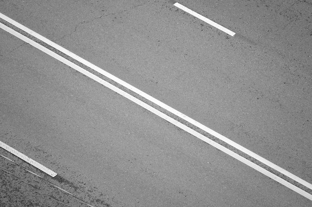 superficie del vialetto di asfalto con segnaletica orizzontale due linee continue, in bianco e nero incolore, vista dall'alto