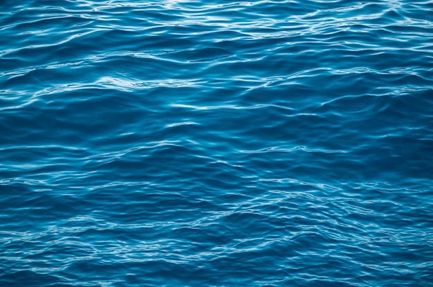 superficie dell'acqua blu con riflessi di luce solare brillante acqua in primo piano sullo sfondo del mare o dell'oceano