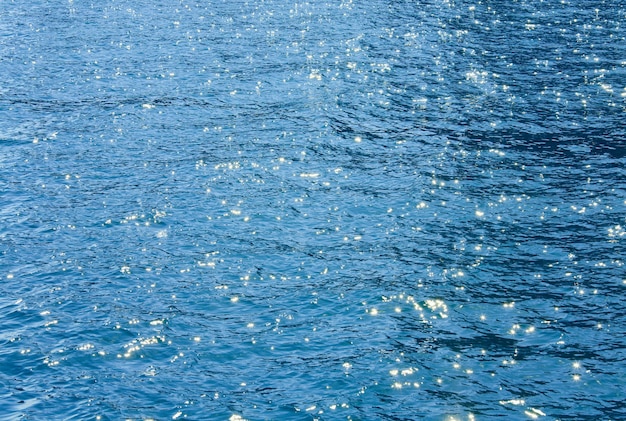 Superficie dell'acqua di mare azzurra con increspature e riflessi del sole