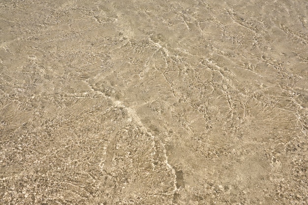 Superficie di acqua chiara sulla spiaggia sabbiosa tropicale in Creta Grecia.